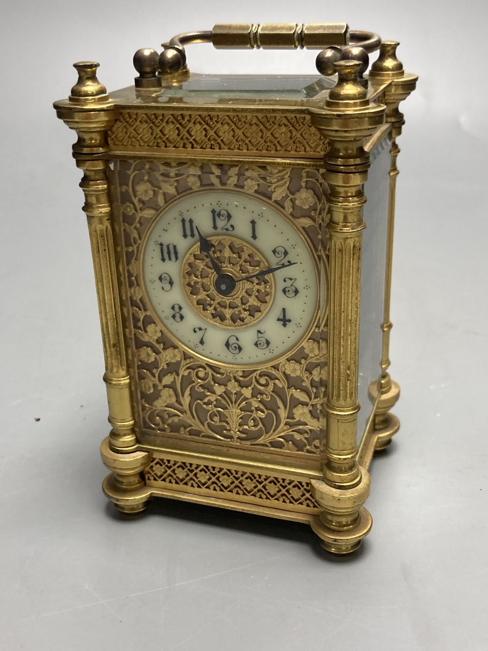 A brass timepiece with four glass panels and filigree decoration